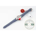 The full watch laid flat, blue alligator strap extended beside its factory tag