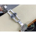 Deployment clasp folded open above the cushion, stone-set links either side