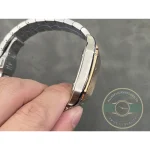 Case edge and bracelet arc held against the grey bench, gold bezel catching light