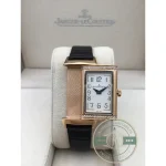 Rose gold tone rectangular case of the JLC Reverso replica at an angle on its cradle