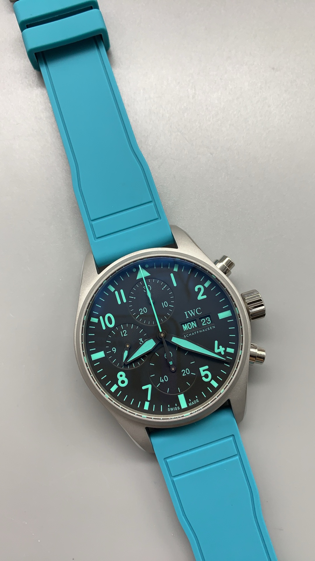 Teal subdial hands set against a sunray-brushed dark grey ground