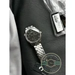 Polished applied 12 and dart indices lifting off the dark dial under direct light