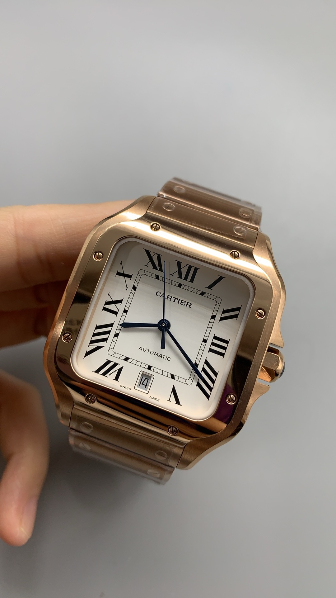 Rose gold case tilted in the hand, date aperture open beneath the Roman six