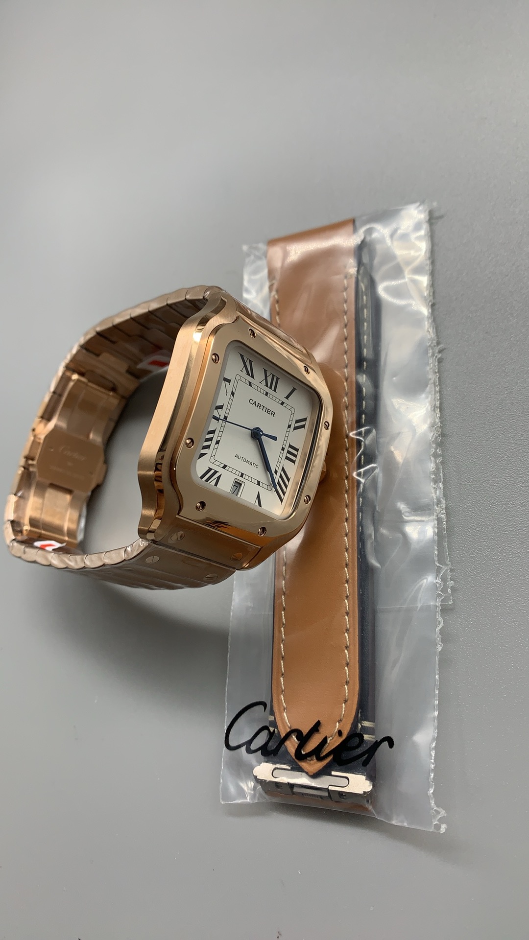 Watch beside a spare leather strap still sealed in its Cartier sleeve