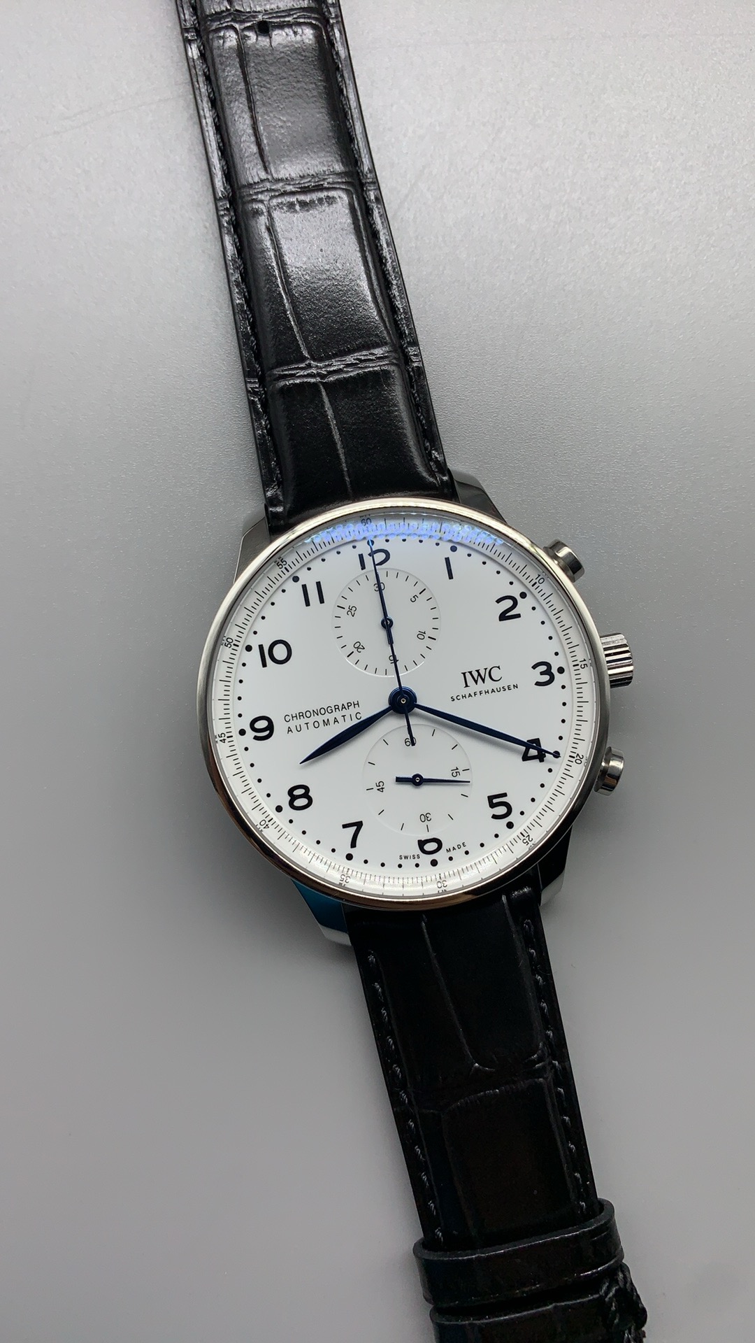 Heat-blued steel leaf hands travel over a white chronograph ground