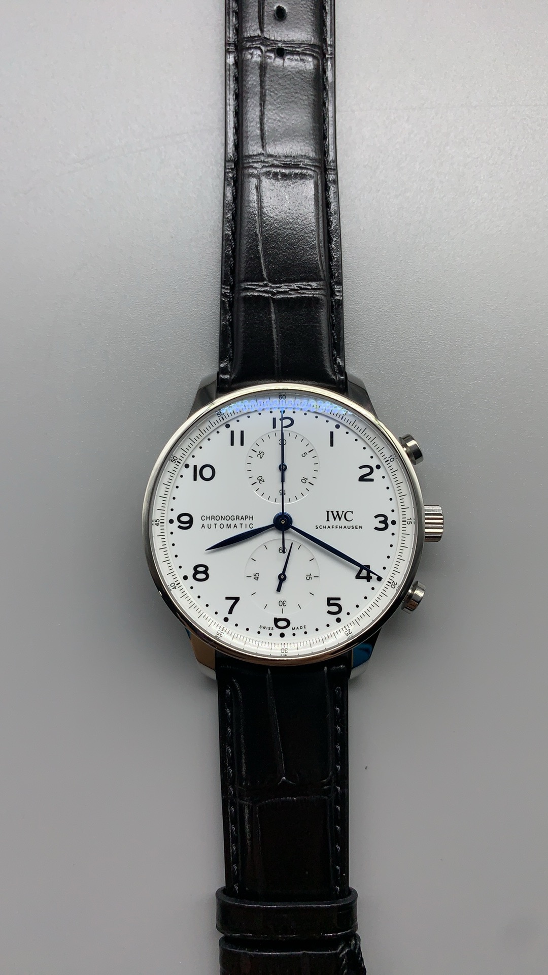 Coated sapphire curves above the white lacquer of this chronograph dial