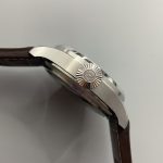 A crown sized for gloved hands, turned solid from steel at the case side