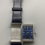 Steel pin buckle closed on the blue leather strap with the tail tucked through the keeper