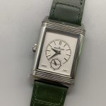 Steel Reverso case caught mid-flip inside the cradle, both halves of the Art Deco frame visible