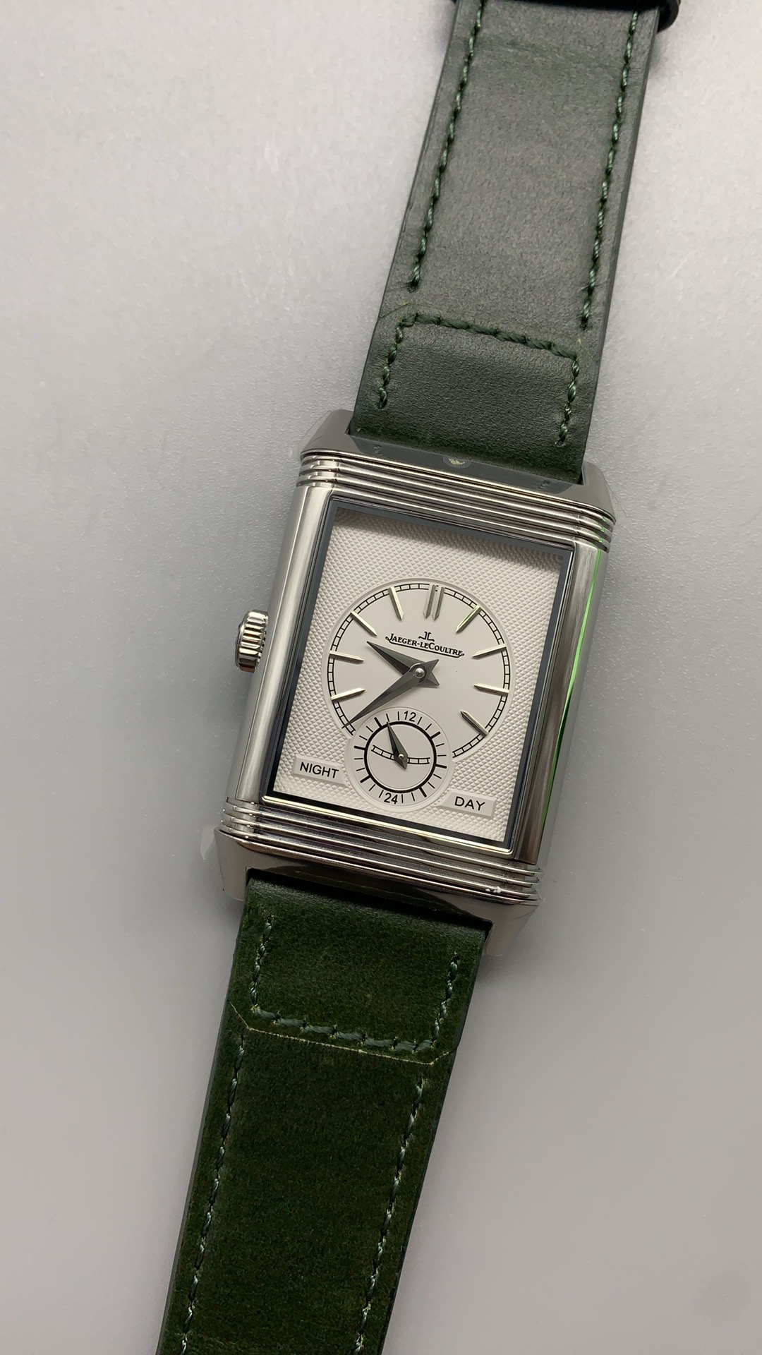 Steel Reverso case caught mid-flip inside the cradle, both halves of the Art Deco frame visible
