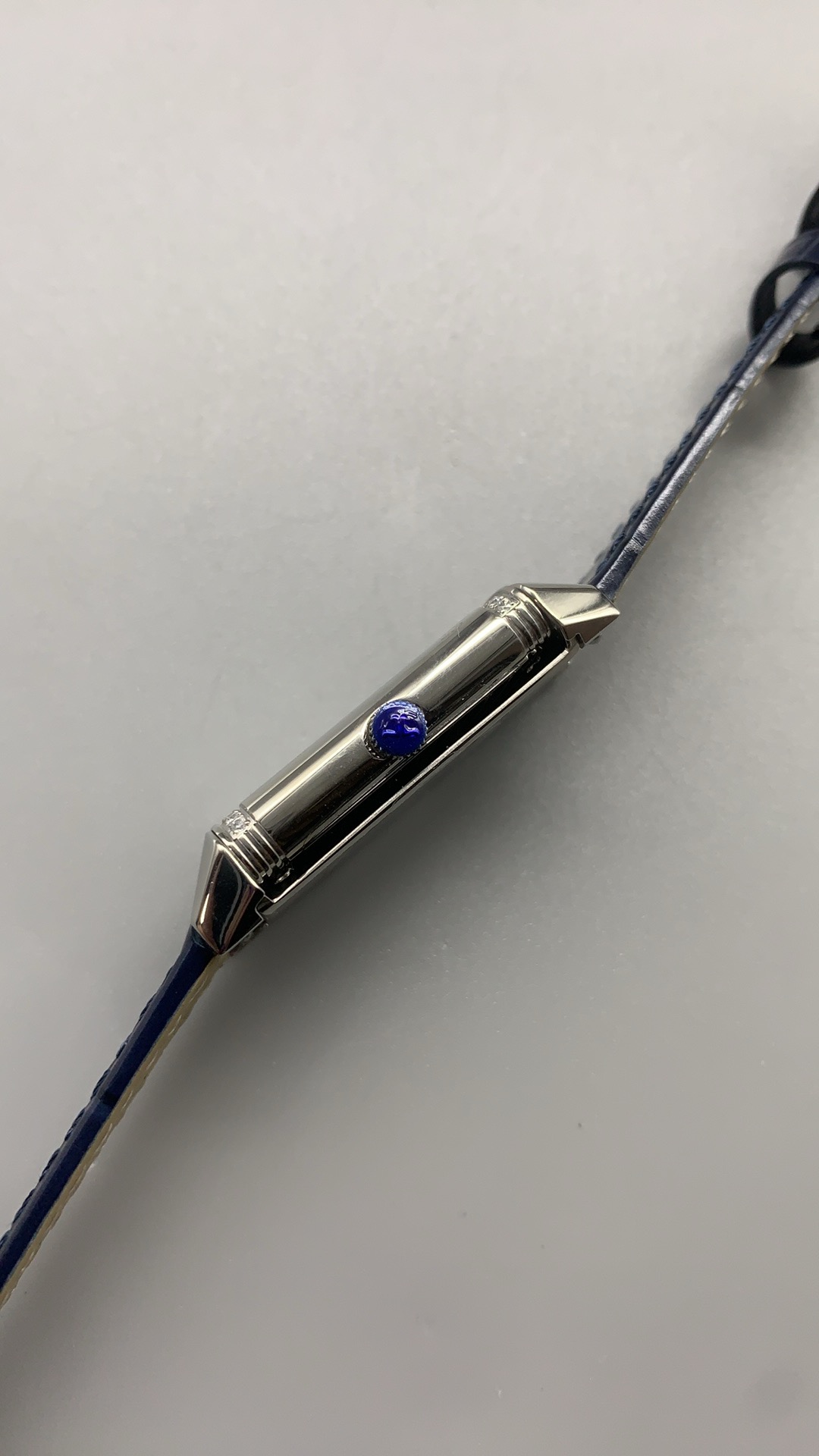 Flat lay of the Q3288420 replica with the blue alligator strap coiled beside the steel case