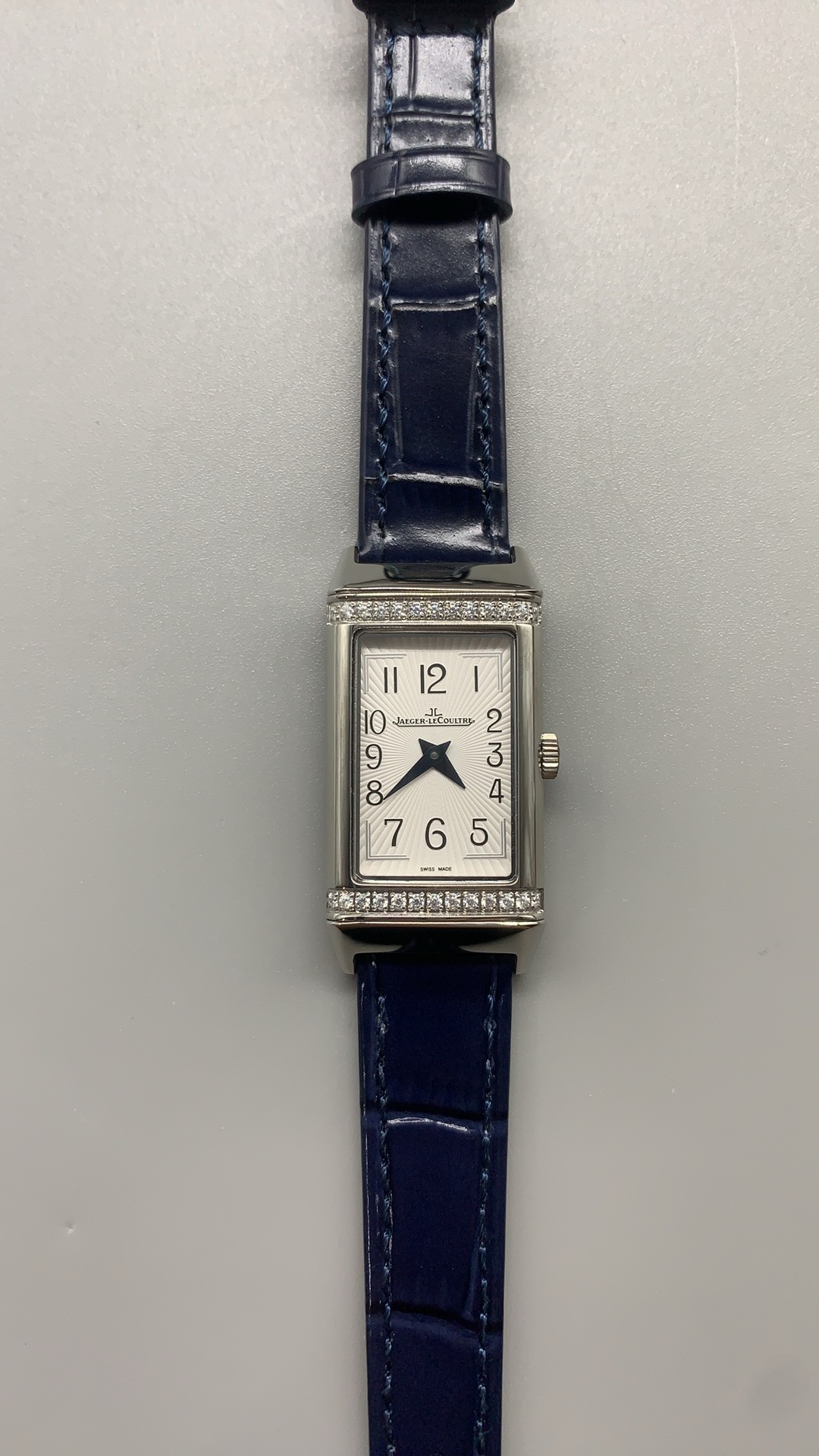 Blue alligator strap scales photographed beside the diamond-set steel cradle of the Reverso