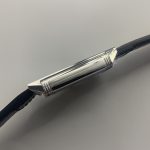 Thin dark hour and minute hands reaching the printed track of the white Reverso dial