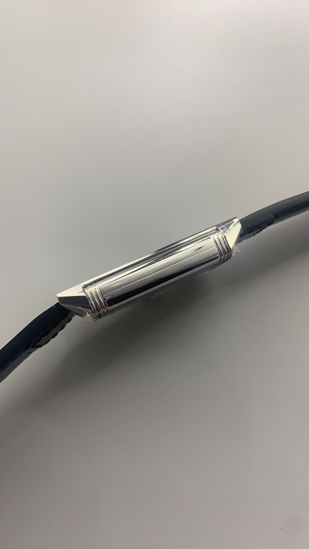Thin dark hour and minute hands reaching the printed track of the white Reverso dial