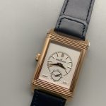 Side profile of the rose gold Reverso Duoface clone, flat case height beside the blue leather strap